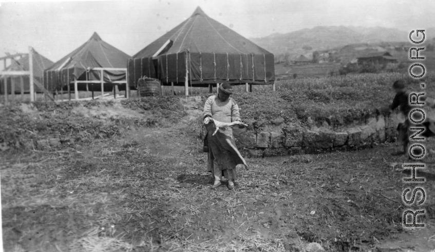 A woman in China holds a freshly skinned piece of vital protein--a cat or dog or similar. During WWII.