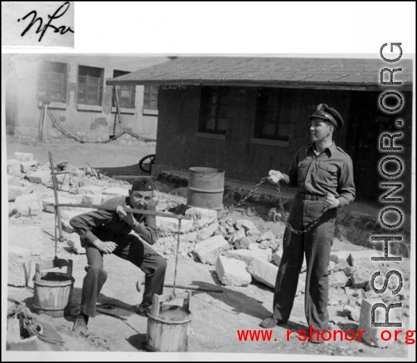 A GI tries out a carrying pole with two buckets in China during WWII.