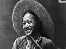 Local people in China: A smiling man stands in front of a large fuel tank.  From the collection of Eugene T. Wozniak.