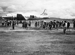 Local laborers working on construction of airbase at Luliang, China, with a C-54 transport in background. During WWII.
