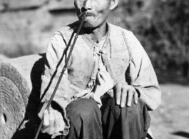 Local man in China during WWII: A man in Yunnan smoking a long pipe. During WWII.