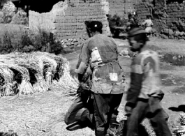People in a local village in Yunnan province, China, threshing grain by striking the rice straw against old wooden wheels. During WWII.