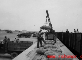 GIs moving aerial bombs between trucks and train in the CBI during WWII.