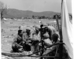 On the ground in the midst of air drop parachutes, a GI coordinates with a group of Chinese soldiers.