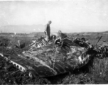 A GI examines the wing of a crashed aircraft in the CBI during WWII.