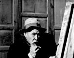 An elderly Chinese man in Liuzhou (based on the inverted sign behind him) smokes a cigarette during WWII.