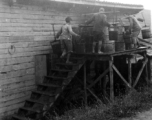 Laborers filling water cistern (of 55-gallon drums) at an American base in SW China during WWII.
