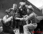 Smiling GIs pose with unhappy small child from poor family in China, during WWII.
