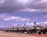 P-40Ks parked in a row in China during WWII, probably in Yunnan province, displaying the 26th Fighter Squadron "China Blitzers" badge on their sharkmouth.